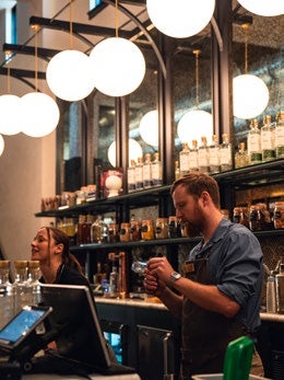 A bartender at Hush and Whisper Distilling cleans a glass